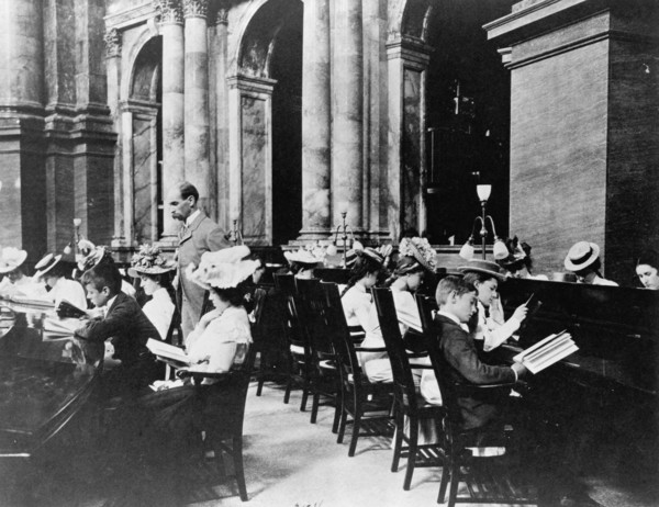 Students in the Reading Room of the Library of Congress with the Librarian of Congress, Herbert Putnam, watching, (1899?).