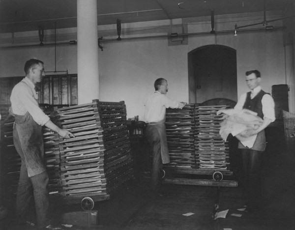 Workers moving newly printed currency into a drying box where sheets will dry before...c1890. Creator: Frances Benjamin Johnston.