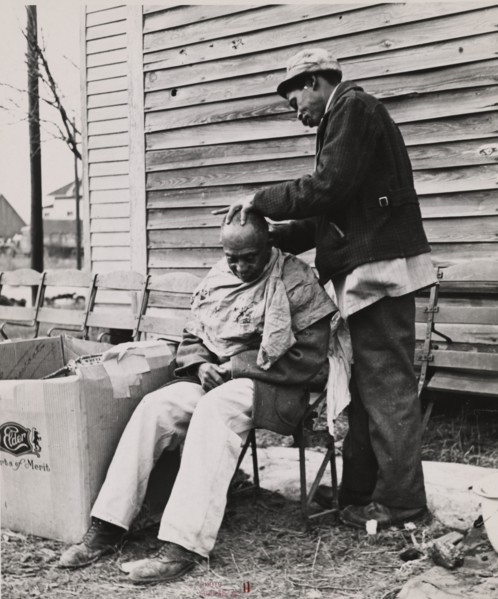 Negro getting a haircut in front of church which houses flood refugees. Sikeston, Missouri, 1937-02.