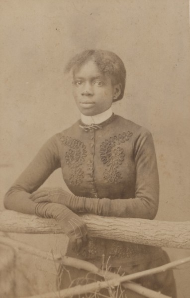 Unidentified young woman wearing gloves, leaning on prop fence, c1880. Creator: H. A. Insley.
