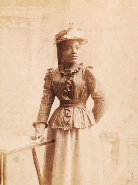 Woman in hat decorated with flowers, and striped blouse, (1900-1950?). Creator: Madison Art Studio.