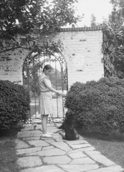 Brady, Genevieve, Miss, with dog, standing outdoors, between 1928 and 1931. Creator: Arnold Genthe.
