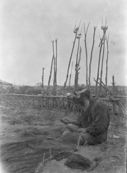 Ainu seated outside working on nets, 1908. Creator: Arnold Genthe.