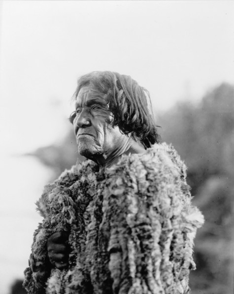 Mohave man, half-length portrait, facing left wearing "primitive" robe of rabbit skin, 1907. Creator: Edward Sheriff Curtis.