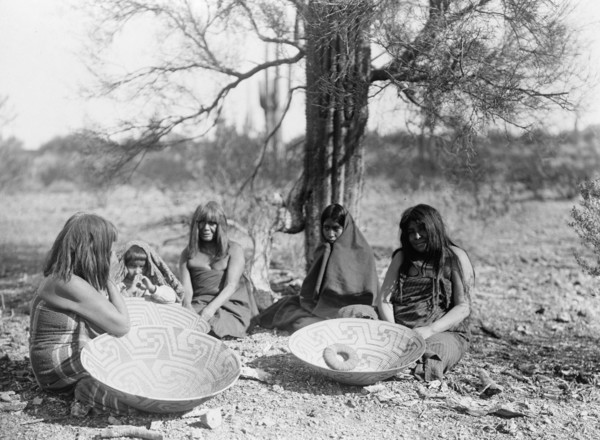 Maricopa group, Arizona. Four women and a child seated on ground with three large basket trays,c1907 Creator: Edward Sheriff Curtis.