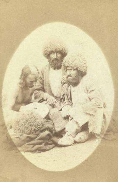 Full-length portrait of three men, seated on ground, facing front, between 1870 and 1886. Creator: Unknown.