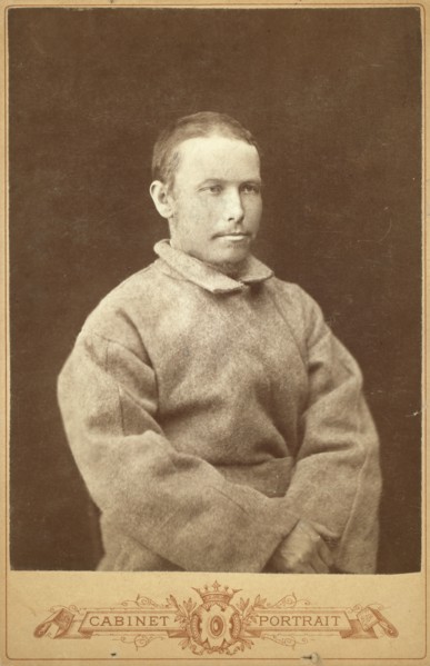 Half-length portrait of a man in convict coat, seated, facing right, between 1880 and 1886. Creator: Unknown.