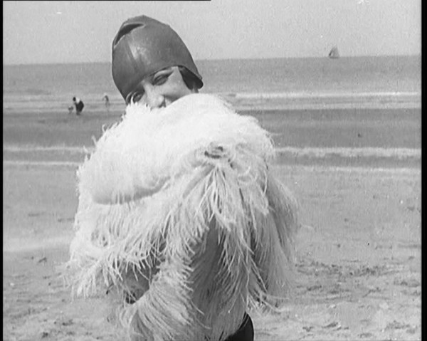 Female Civilian Wearing a Swimsuit Holding a Feathered Parasol at the Beach, 1920. Creator: British Pathe Ltd.
