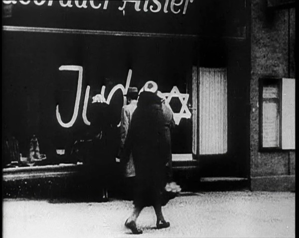 Civilians Looking at  Shop Window with Graffiti Reading: ‘Juden’ on it, 1933. Creator: British Pathe Ltd.