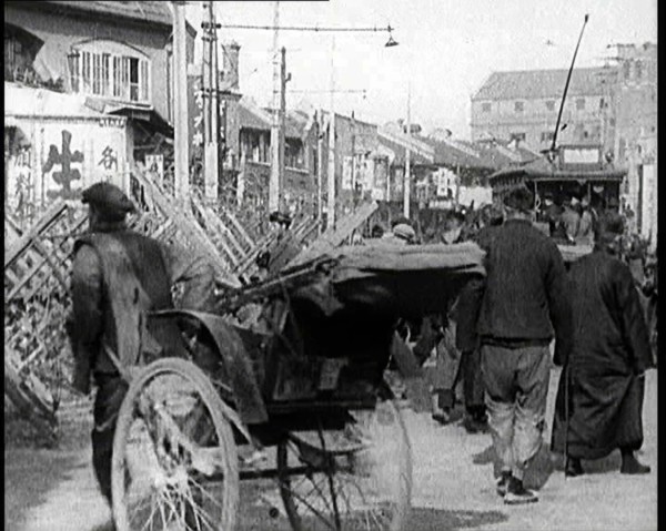 A Male Chinese Civilian Pulling Rickshaws Through the Streets of Shanghai Past Barricades, 1920s. Creator: British Pathe Ltd.