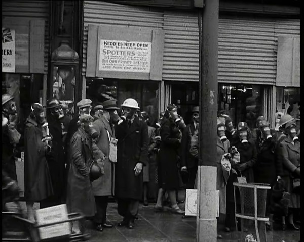 Men and Women Waiting on a Pavement Wearing Gas Masks, 1939. Creator: British Pathe Ltd.
