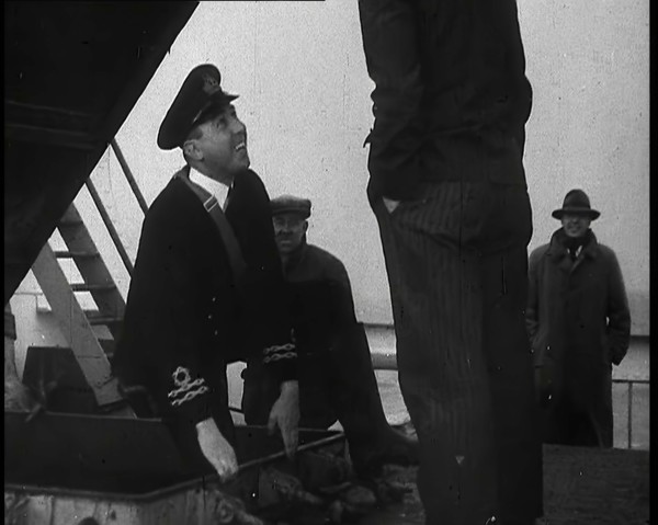 A Male Customs Official Standing by a Hatch and Talking to a Man on Board a Large Ship in..., 1939. Creator: British Pathe Ltd.