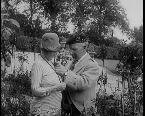 Sir Harry Lauder Giving Flowers to His Wife, Lady Ann Lauder, at Home in Scotland, 1920s. Creator: British Pathe Ltd.