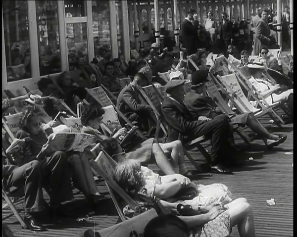 Lines of Men and Women Sitting in Deckchairs on a Pier at  Brighton With Several Reading..., 1939. Creator: British Pathe Ltd.
