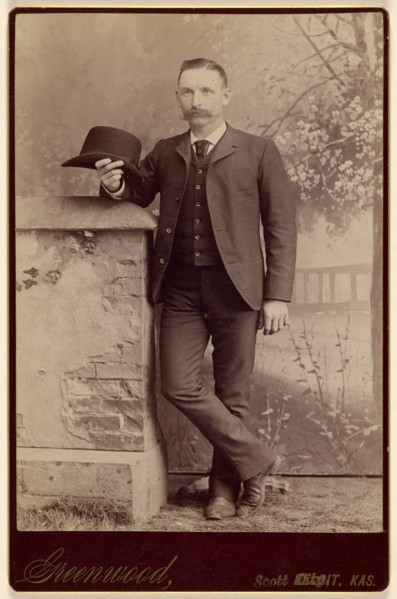 Studio portrait of a man holding a hat, about 1885. Creator: WH Greenwood.