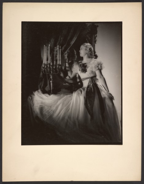 Woman lighting candelabra, 1930s. Creator: Gunther Krampf.