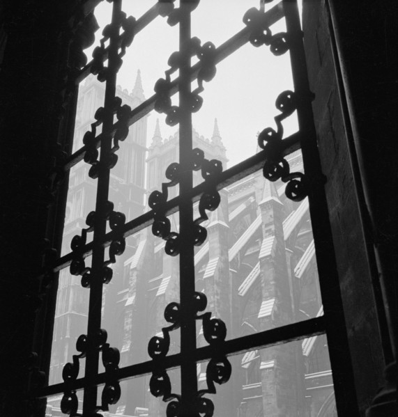 Looking through a wrought iron decorative window grille towards the south facade of the Westminster