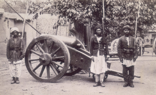 Three Afghan soldiers standing next to a cannon, Afghanistan, 1880s. Their rifles have bayonets