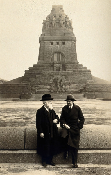 Georg Sticker and an unknown companion, in front of a war memorial (?). Creator: Unknown.