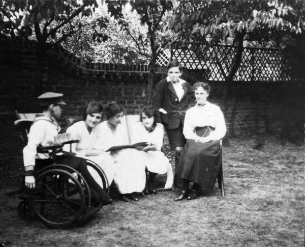 A physically disabled boy sitting in a wheelchair in a garden,  c1910/1925. Creator: Unknown.