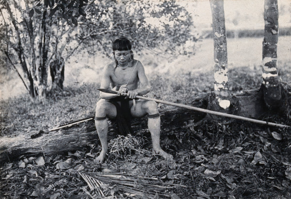 Sarawak: a Kenyah worker tying a spearhead to a blowpipe, c1900. Creator: Unknown.