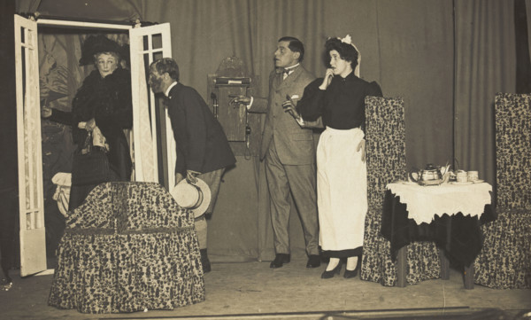Amateur actors, one in drag, perform a scene on stage, [between 1910 and 1919?]. Creator: Unknown.