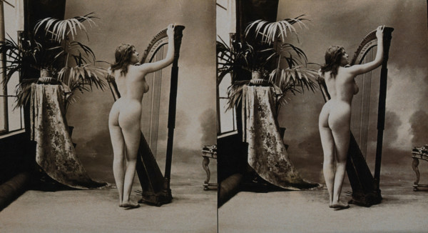 A young woman posing naked in a photographic studio, standing with her back to the camera..., c1900. Creator: Unknown.