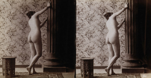 A young woman posing naked in a photographic studio, with her back to the camera looking..., c1900. Creator: Unknown.