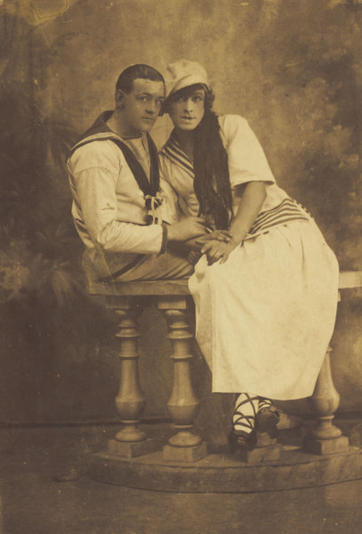 Two sailors, one in drag, embracing while sitting on a stage balcony, (between 1910 and 1919?). Creator: Unknown.