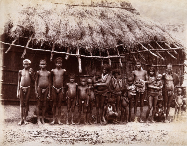A group of adults and children standing in a line outside a bamboo hut with a thatched..., 1896/1897 Creator: Unknown.