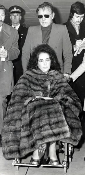 Elizabeth TAYLOR in a wheelchair with Richard BURTON, 1973