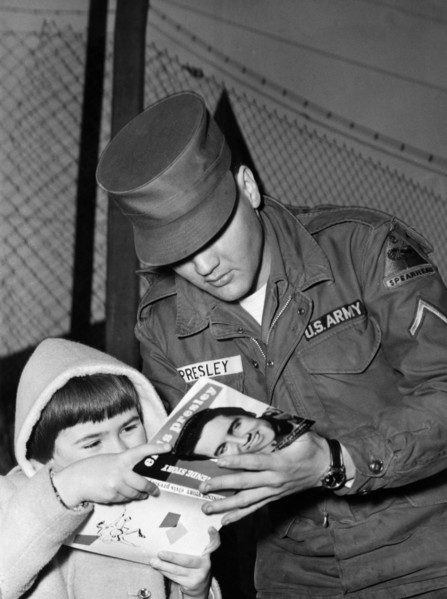 Elvis PRESLEY gives an autograph to a child in 1959