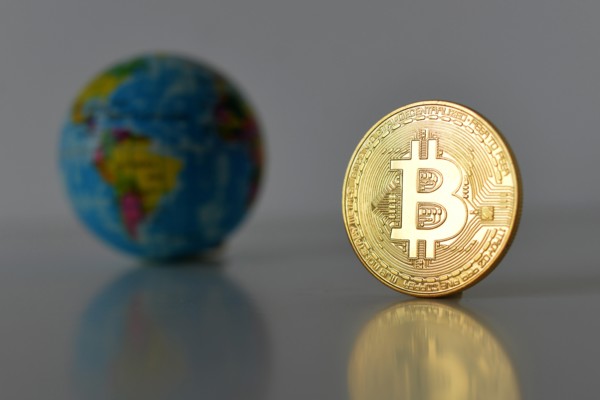 Bitcoin concept. World economy concept. New world currency. Golden coin bitcoin and globe.
