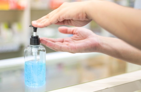 Female hand pressing alcohol gel or sanitizer pump bottle for washing hand in hospital or public area. Coronavirus infection or COVID-19 outbreak prev
