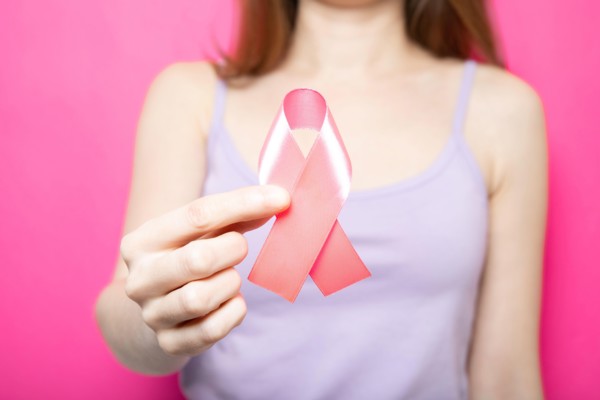 The girl is holding a pink ribbon in her hands. Breast Cancer Symbol