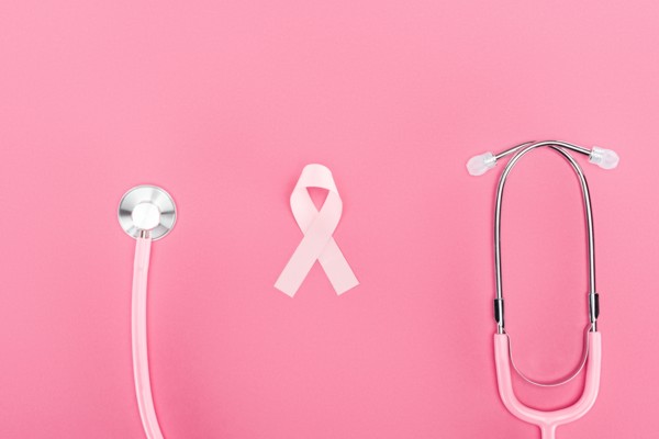 top view of stethoscope and pink breast cancer symbol on pink background