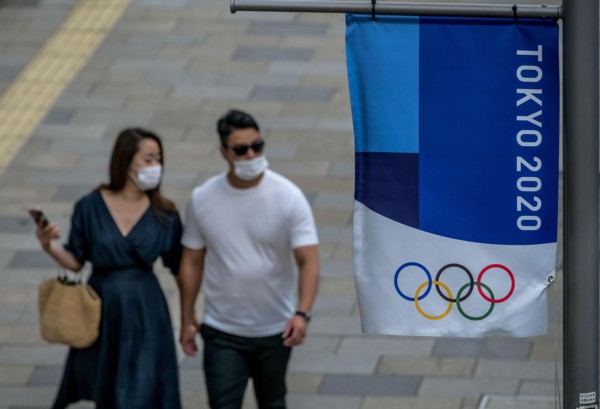 Tokyo, Japan. 09 May, 2021. A couple walks by a Tokyo 2020 flag ahead of the protest against the Tokyo Olympics in front of the New National Stadium, the main stadium for the Tokyo Olympics. Credit: A...