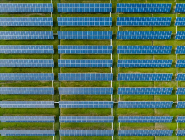 Aerial view of Solar Panels Farm with sunlight. Drone flight over solar panels field, renewable green alternative energy concept.