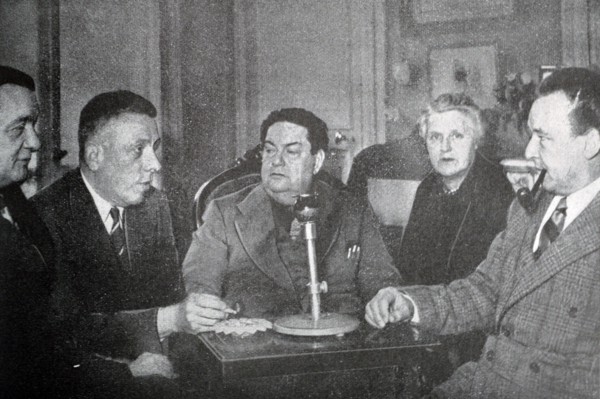 Black and white photograph of Darius Milhaud (1892-1974), French composer, at an evening party with French pianist and teacher Marguerite Long (1874-1966), French composer and pianist Francis Poulenc ...