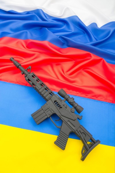 Russian and Ukrainian flags with black painted toy assault rifle. For Ukraine-Russia crisis, Russian invasion, tensions and war in Ukraine.