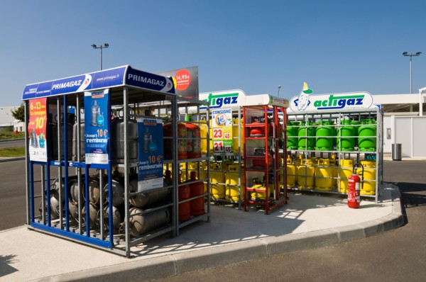 Household gas / gaz bottles in racks at supermarket garage, France.