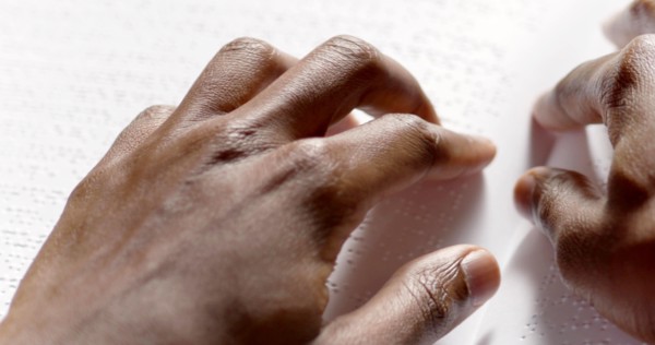 A black man is reading braille