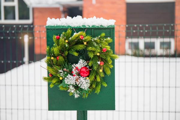 Domestic mail box decorated with spruce tree Christmas wreath outdoors in snowy winter day. Holiday moods.