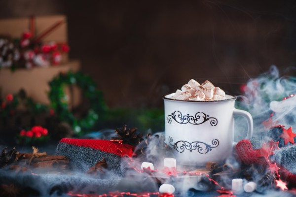 Hot chocolate with marshmallows in a cozy enamel mug with steam and Christmas decorations