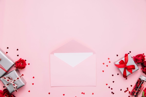 Saint Valentine day card template, greeting, wedding invitation flat lay. Top view on pink background with opened pink envelope with blank sheet message, gray gift boxes decorated with heart confetti