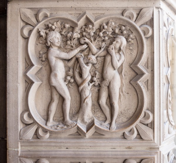 Relief carving of Adam, Eve and the Tree of Knowledge. Eve eats an apple with Adam looking on with a serpent