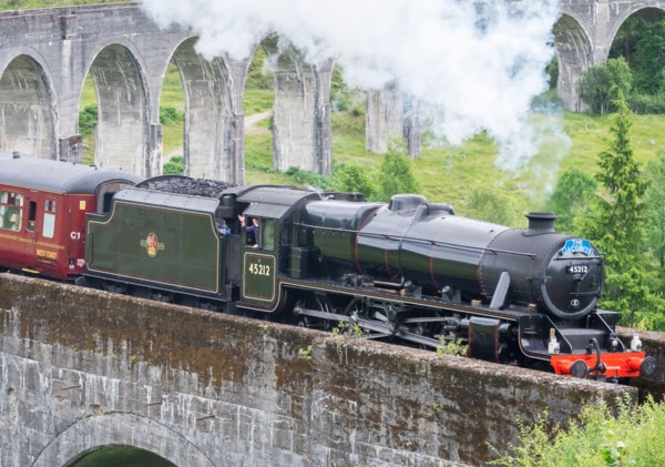 Glenfinnan,Inverness-shire,Scottish Highlands-July 21 2022:The train driver waves and lets off steam to onlookers,as the iconic train,shown in Harry P