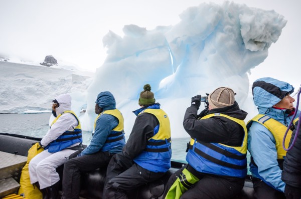 ANTARCTICA - A group of tourists cruise on the side of an inflatable boat past an a small iceberg in Curtis Bay, Antarctica.