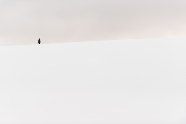 ANTARCTICA - A person hikes to the top of a small snow-covered hill in Hughes Bay on the western coast of the Antarctic Peninsula.
