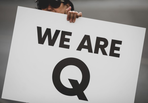 Bucharest, Romania - August 10, 2020: A woman takes part at a protest and displays a Qanon message on a cardboard.